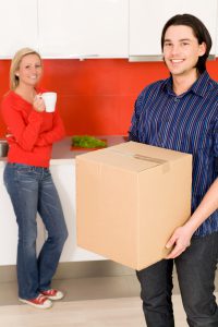 Man holding moving box and woman in background