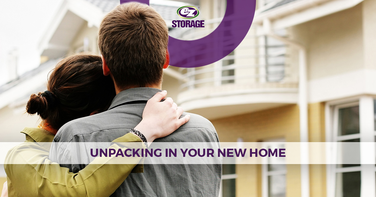 Couple holding each other looking at their new home from outside with text "unpacking in your new home"