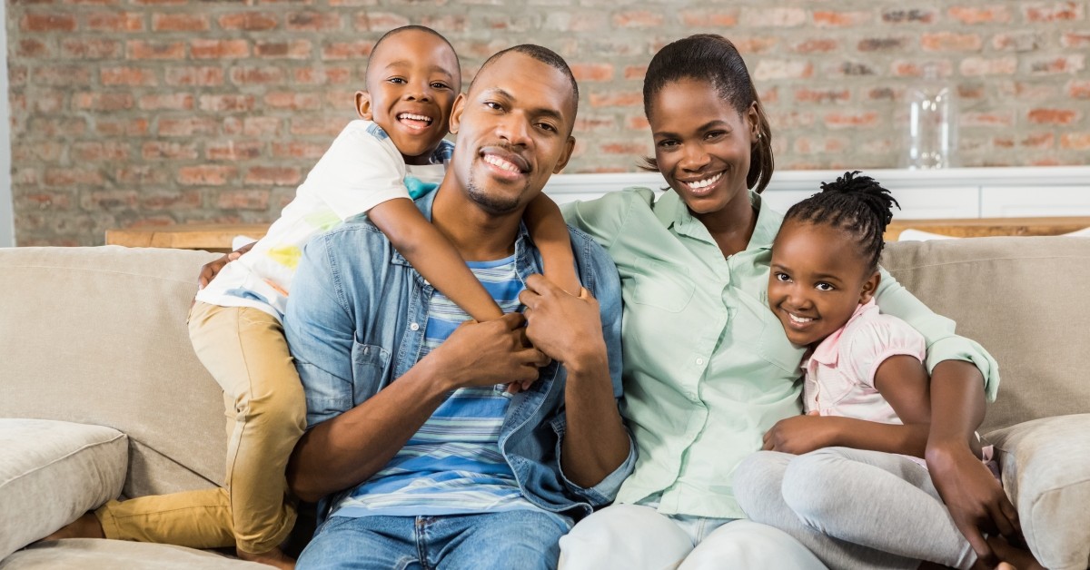 Couple with two kids sitting on couch and smiling