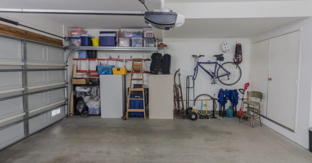 Organized garage with white drywall, shelving units, and wall hangings