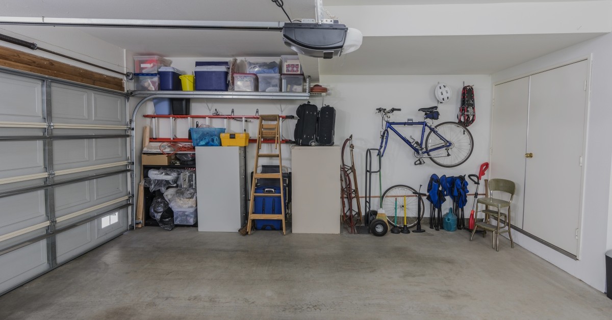 Organized garage with white drywall, shelving units, and wall hangings