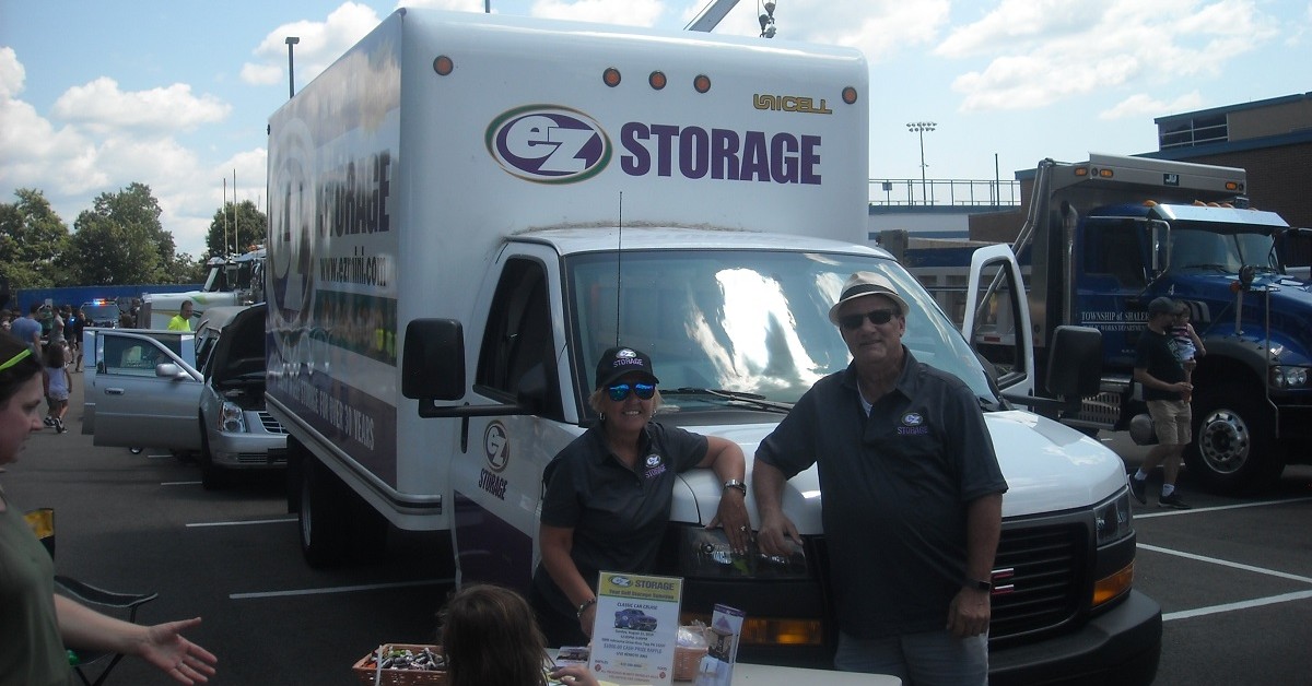 Frontal view of an EZ Storage moving truck with people facing camera & smiling