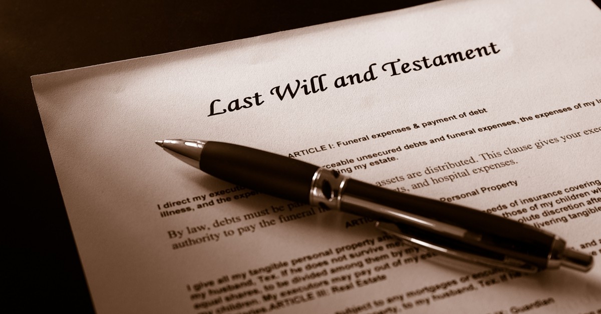 Close up of paper with pen lying atop and text, "Last Will and Testament," and other text.