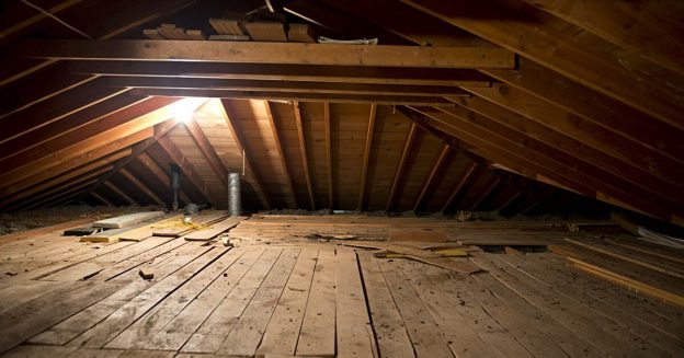 Attic crawl space with exposed floor boards and single light bulb.