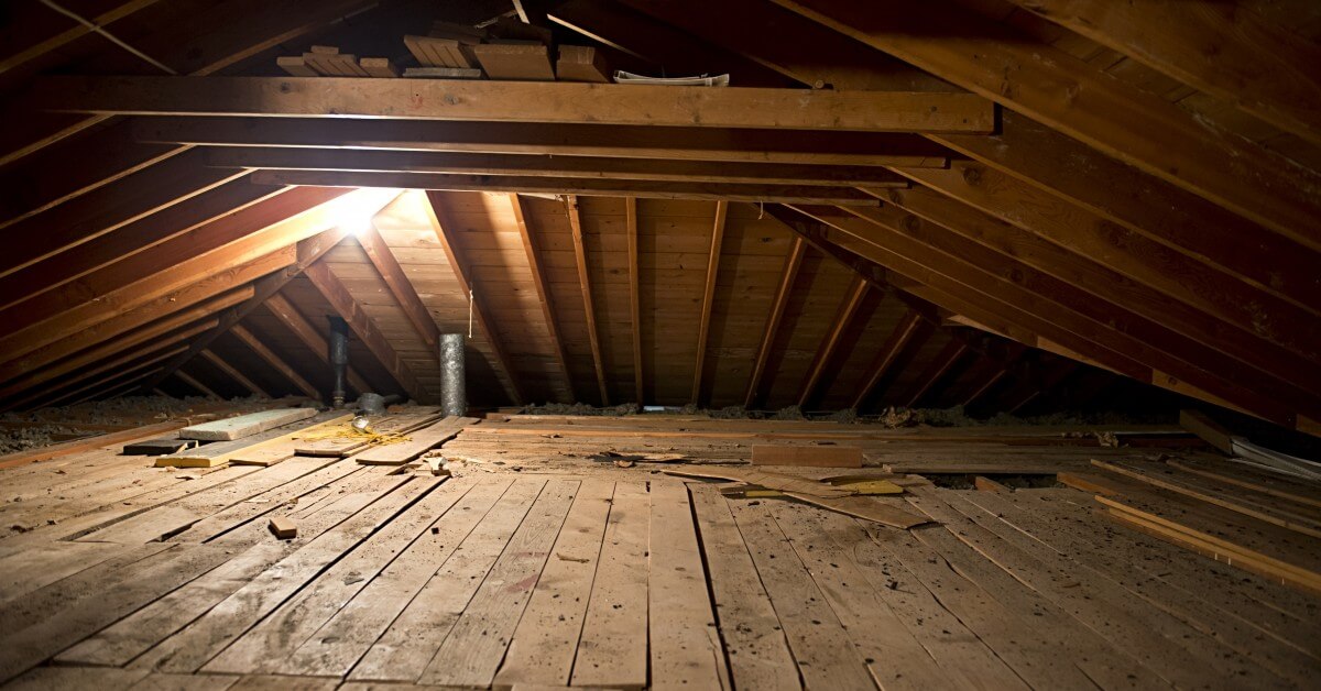 Attic crawl space with exposed floor boards and single light bulb.